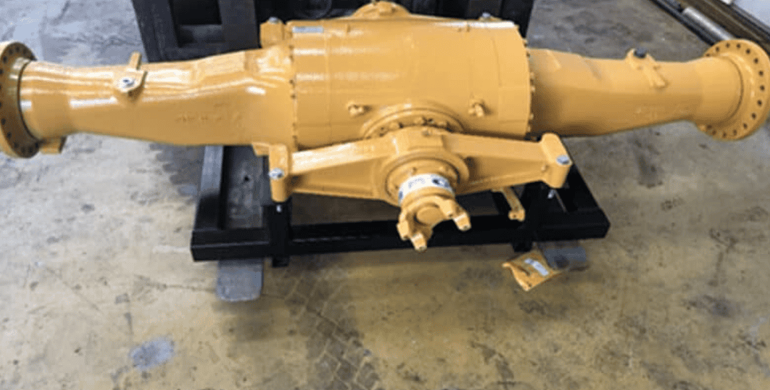A pale yellow transmission part sitting on a concrete surface